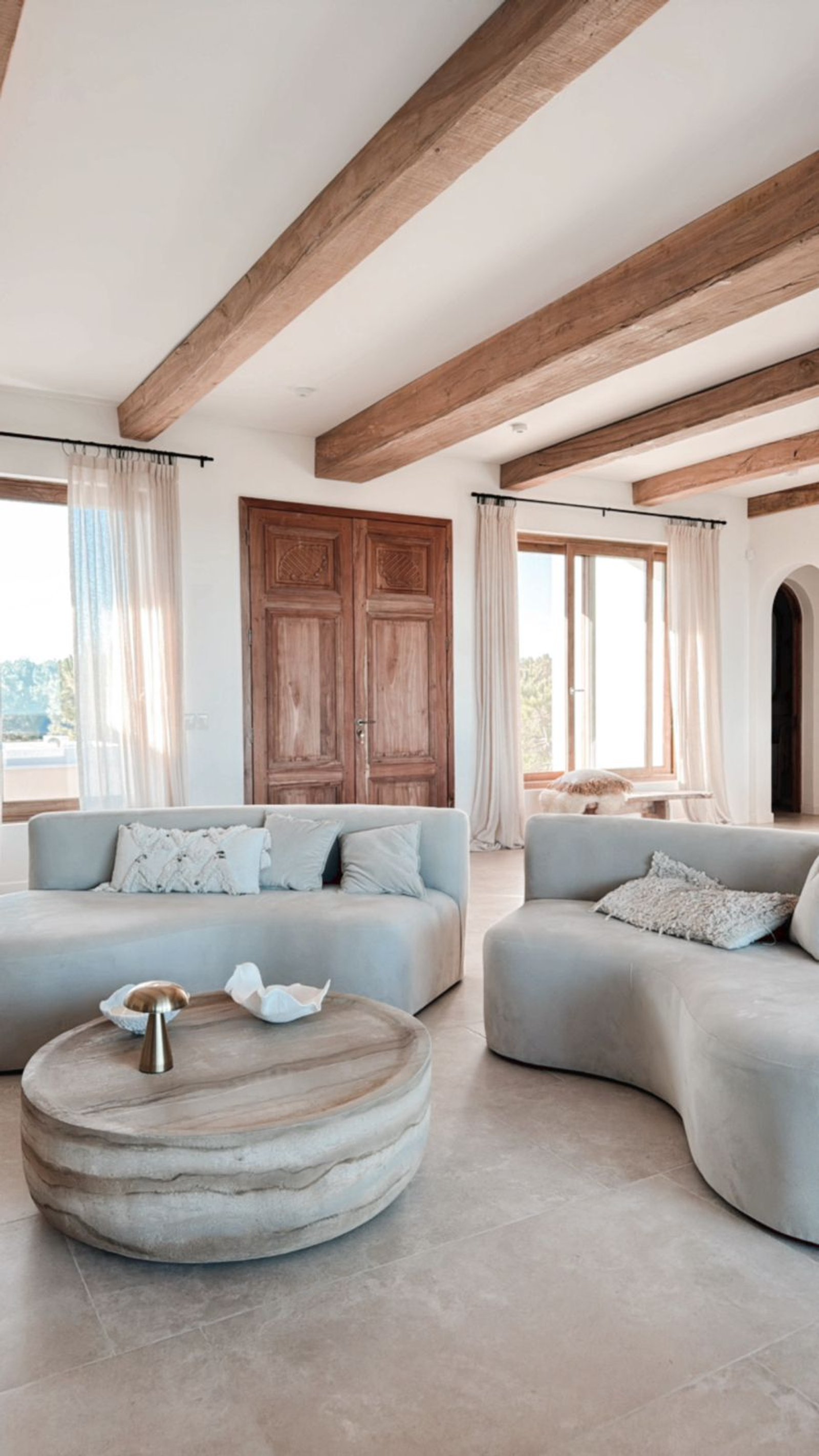 Sala de estar mediterránea con vigas de madera y sofás curvos — proyecto OBRA EL REFUGIO, por ILVA, en Provincia de Buenos Aires
